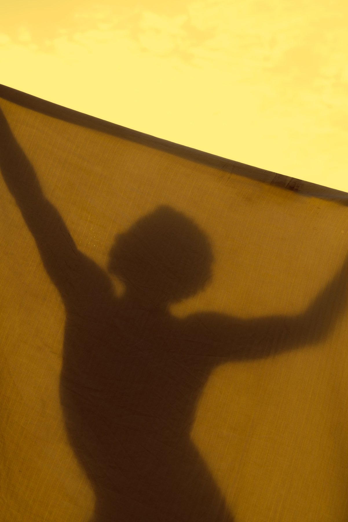 Silhouette with arms raised against golden light